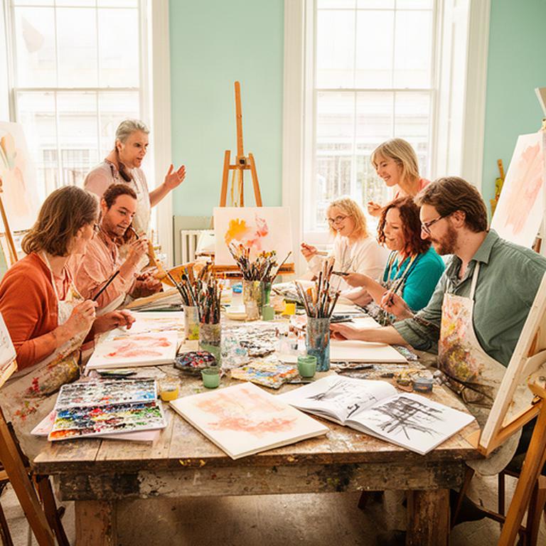 Artists painting together around a large wooden table in a bright Dublin studio